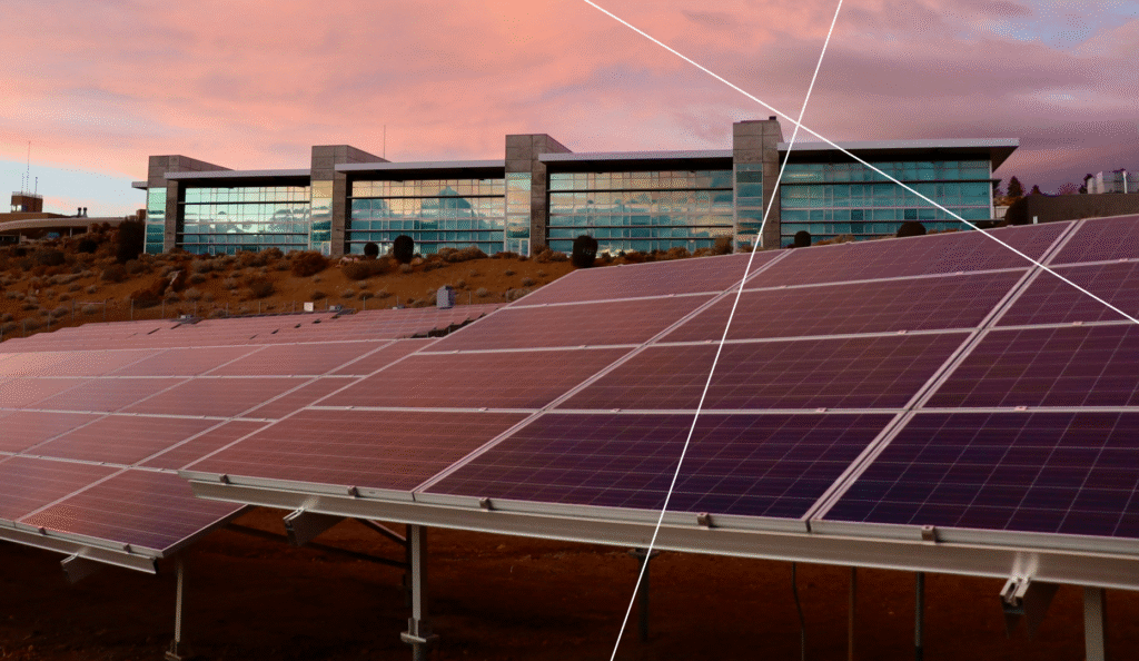 Solar panels in front of a modern glass building at sunset — a representation of renewable energy in smart city infrastructure