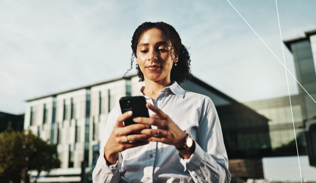 Woman using a smartphone outside a modern city office building, symbolizing digital urban services.